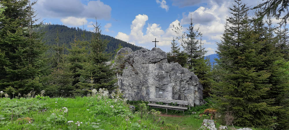 Ein Felsen mit Kreuz und einer Bank davor